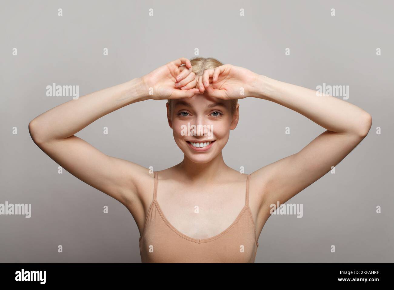Primo piano della giovane donna che tiene le braccia in su e che mostra la sua ascella su sfondo bianco. Foto Stock