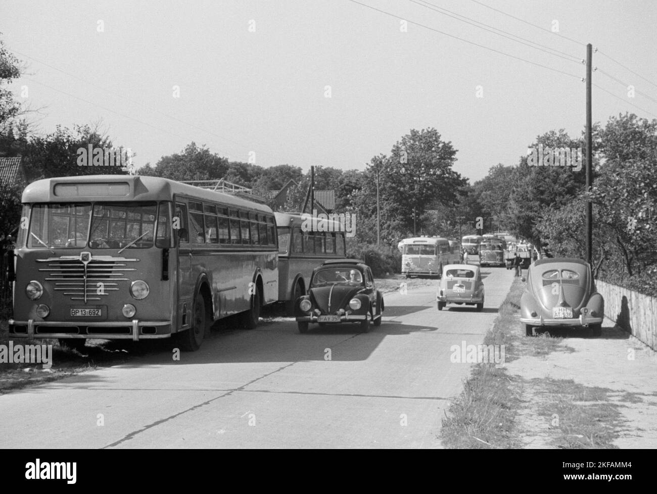 Ein VW Käfer fährt an parkenden Bussen vorbei, Deutschland 1950er Jahre. Un VW Beetle passa davanti agli autobus parcheggiati, 1950s Germania. Foto Stock