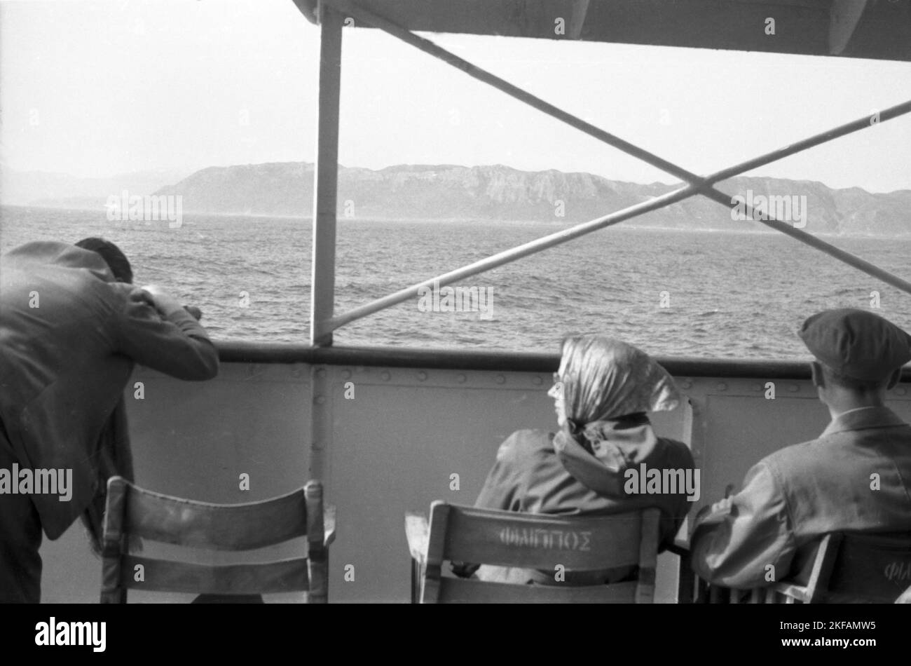 Touristen entspannen an deck ihres Kreuzfahrtschiffes und genießen den Blick aufs Land, Griechenland 1950er Jahre. Turisti che si rilassano a bordo della loro nave da crociera e godendo la vista sulla linea costiera, Grecia, 1950s. Foto Stock