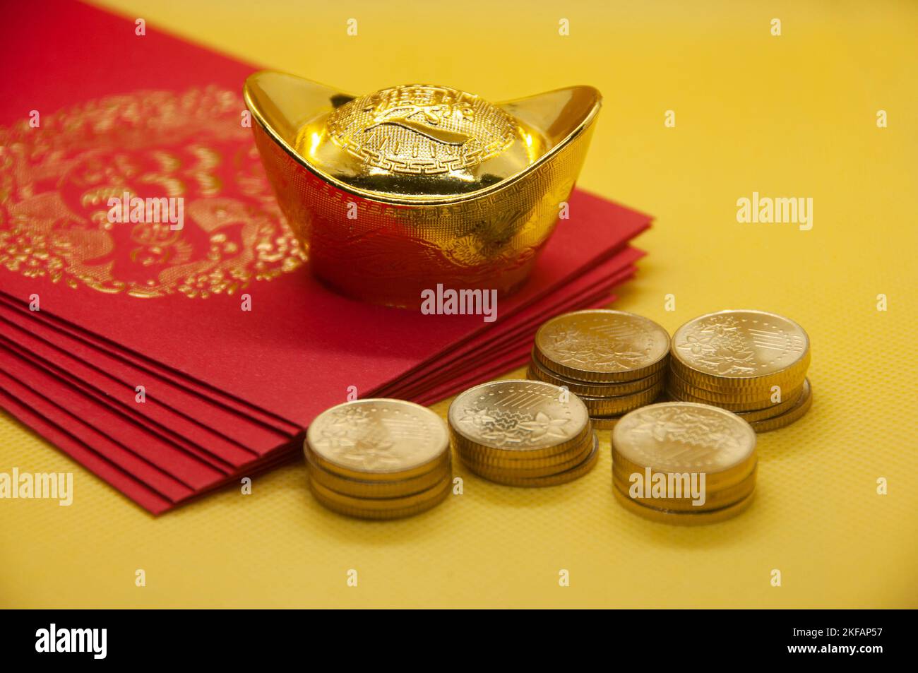 Pacchetti Capodanno cinese con lingotti e monete d'oro cinesi su sfondo giallo con spazio personalizzabile per il testo. Foto Stock