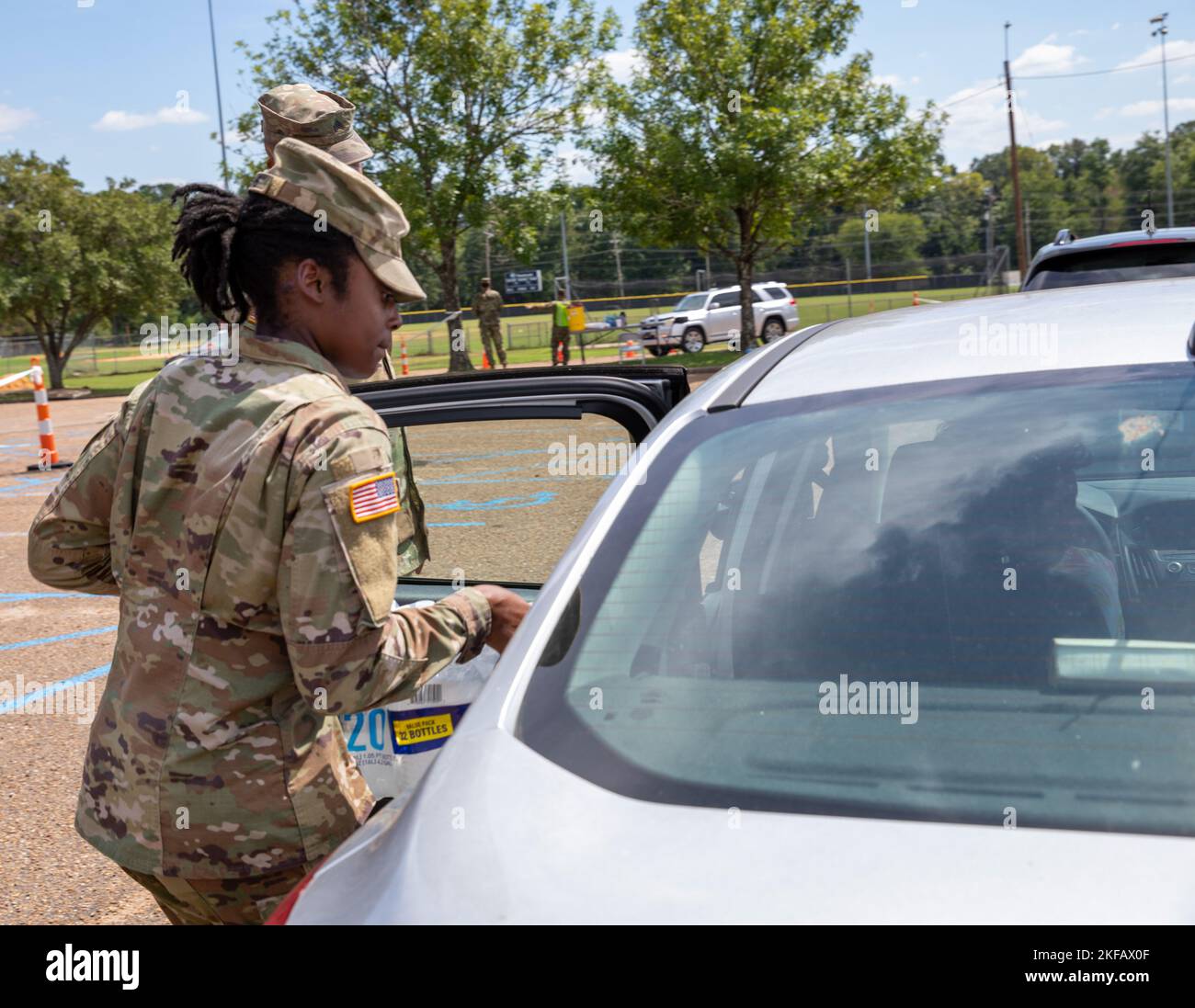 Un soldato con il comando della truppa del 66th, la guardia nazionale dell'esercito del Mississippi, mette l'acqua nel sedile posteriore dell'auto di una persona allo Smith-Wills Stadium di Jackson, Mississippi, 1 settembre 2022. Quasi 600 membri della guardia nazionale del Mississippi sono stati allestiti in sette siti in tutto Jackson per consentire ai residenti di raccogliere acqua in bottiglia e acqua non potabile dai camion delle acque per contribuire ad alleviare alcuni effetti della crisi idrica di Jackson. (STATI UNITI Foto della Guardia Nazionale dell'esercito da parte del personale Sgt. Connie Jones) Foto Stock