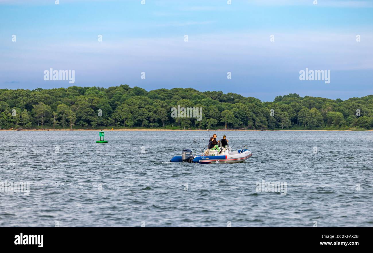Tre uomini in una barca gonfiabile che pesca al largo della costa di isola di riparo, ny Foto Stock