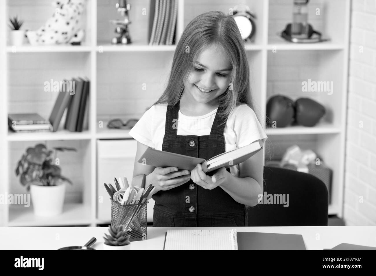 felice bambino leggere libro a scuola lezione in classe indossare uniforme, lettore Foto Stock