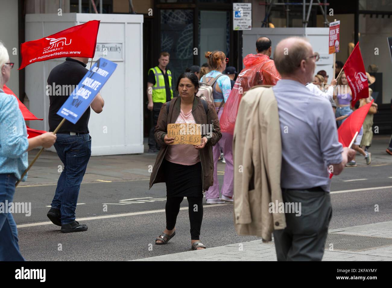 I partecipanti hanno passato un mendicante durante la dimostrazione “noi chiediamo di meglio” chiamata dal TUC in mezzo al crescente costo della vita a Londra. Foto Stock