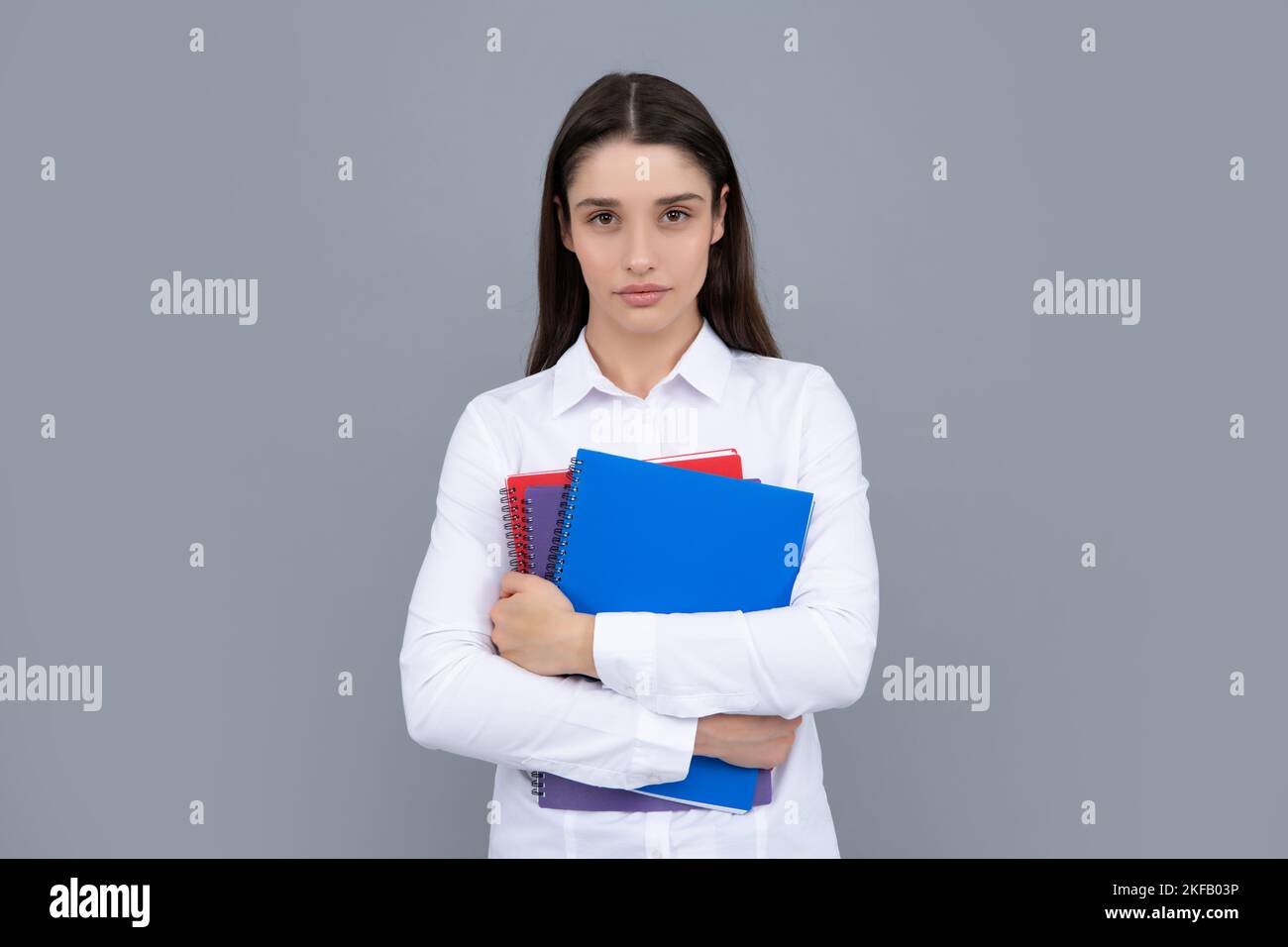 Giovane studentessa in abiti casual, isolato su sfondo grigio studio ritratto. Tenere i notebook. Giovane ragazza allegra attraente studentessa donna. Foto Stock