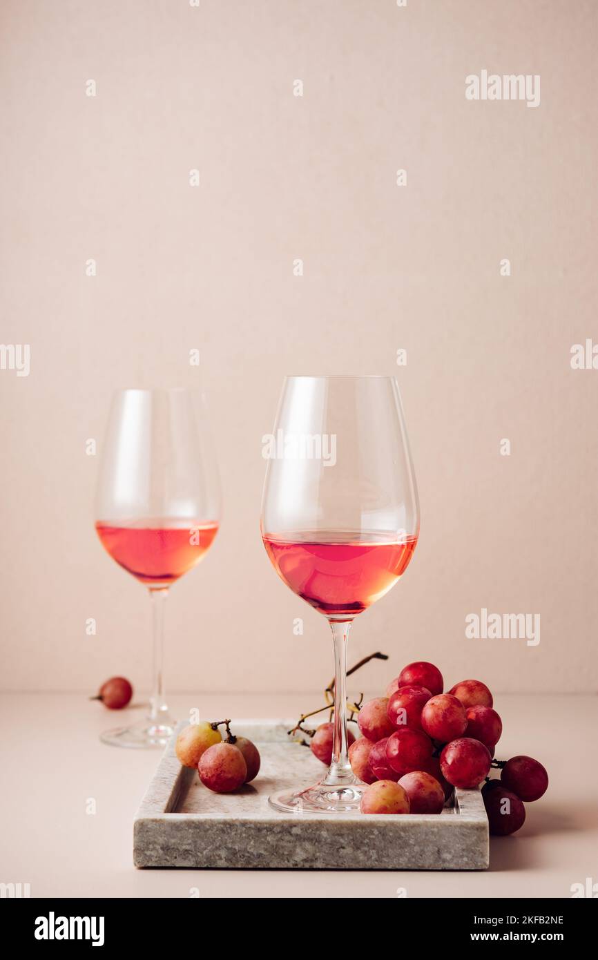 Due bicchieri di vino rosato e un mazzo di uve rosse. Foto Stock