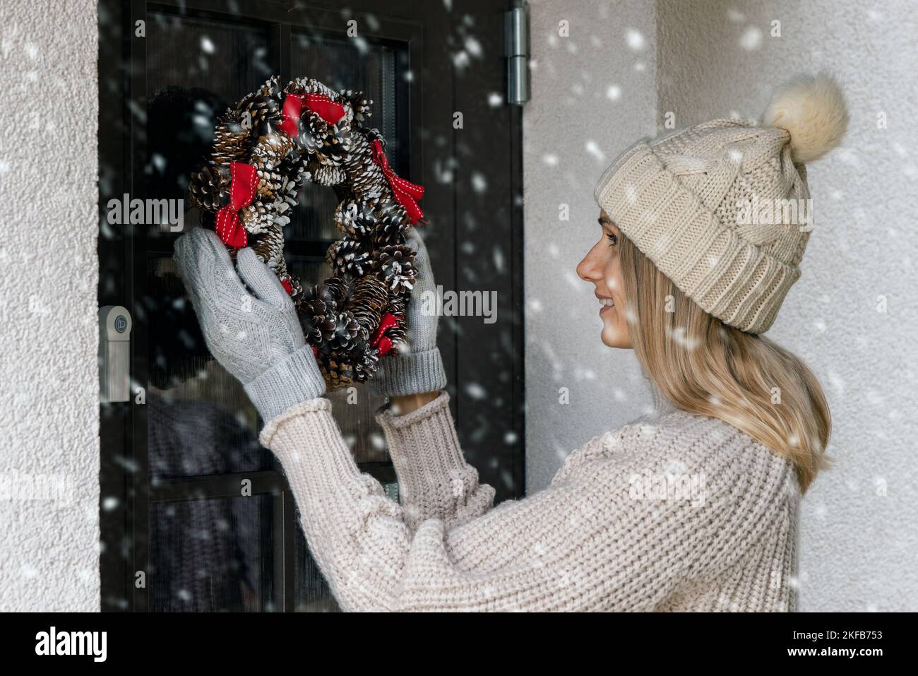 donna appendere una corona di avvento di natale su una porta di casa. decorazione casa Foto Stock