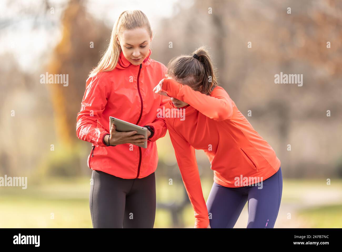 Una giovane trainer femminile e una junior stanno controllando le sue prestazioni sportive su un tablet. Foto Stock