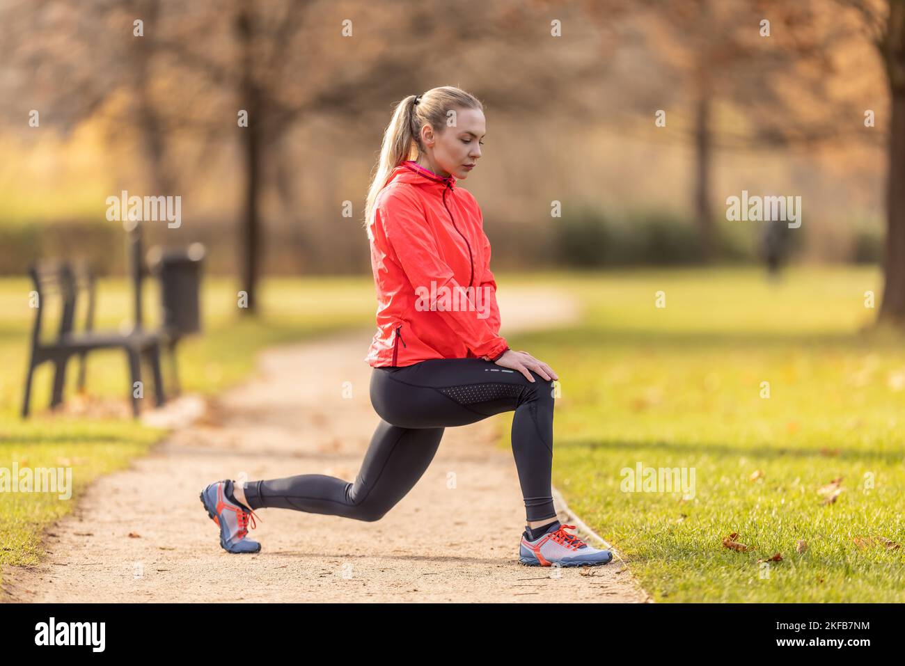Una giovane donna si riscalda prima di fare jogging e riscalda i muscoli delle gambe. Foto Stock