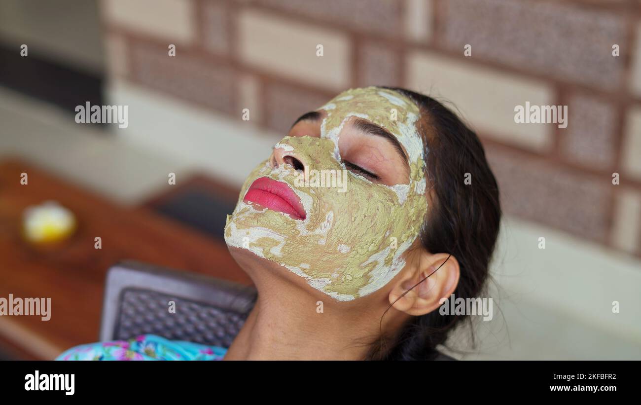 Bella giovane donna che usa maschera facciale fatta in casa sul viso e rilassante a casa. Donne asiatiche con Multani Mitti e rosa pacchetto viso acqua. Ritratto di sp Foto Stock