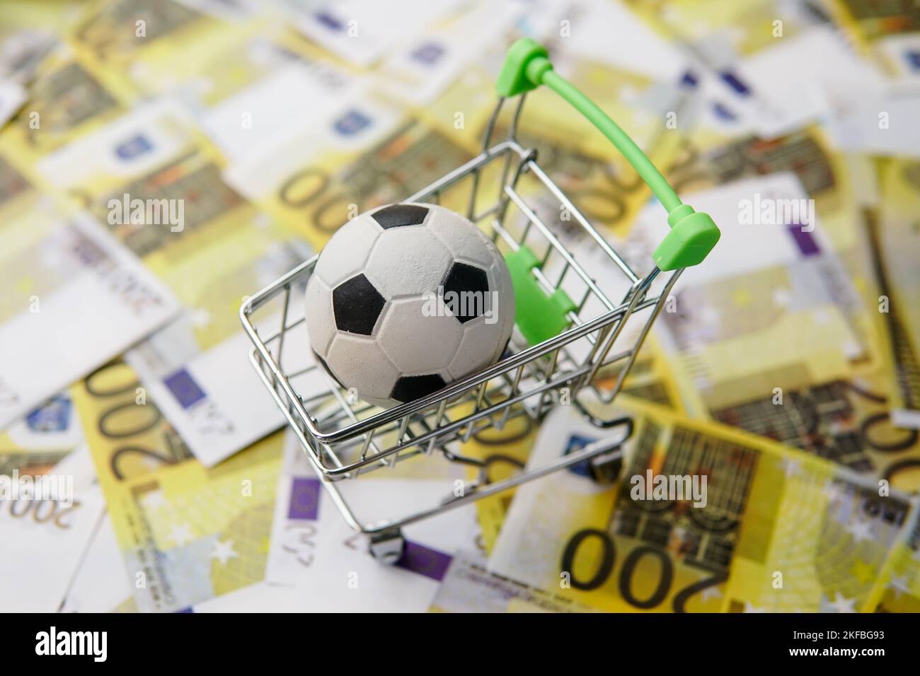 Pallone da calcio nel carrello della spesa sullo sfondo delle banconote in euro. Guadagni della coppa di calcio. Foto Stock