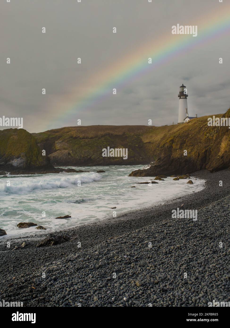 Pittoresco paesaggio marino. Onde oceaniche infurianti, alta costa verde. Un arcobaleno multicolore nel cielo grigio. Oceano dopo la pioggia. Bella natura, ecol Foto Stock