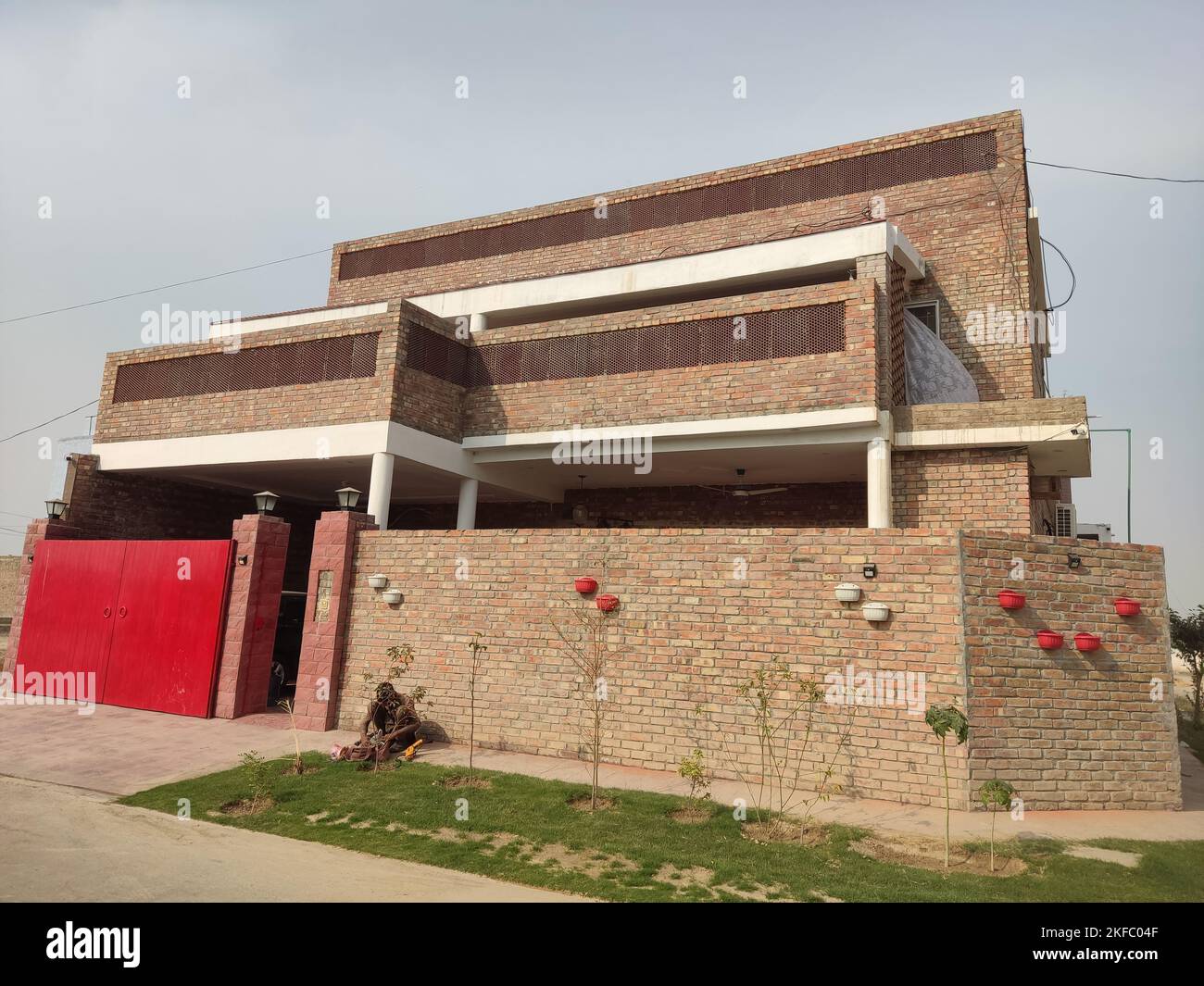 vecchio stile casa in mattoni con cancello rosso, mattoni in costruzione, casa fatta finita con mattoni e vernice bianca e cancello rosso Foto Stock
