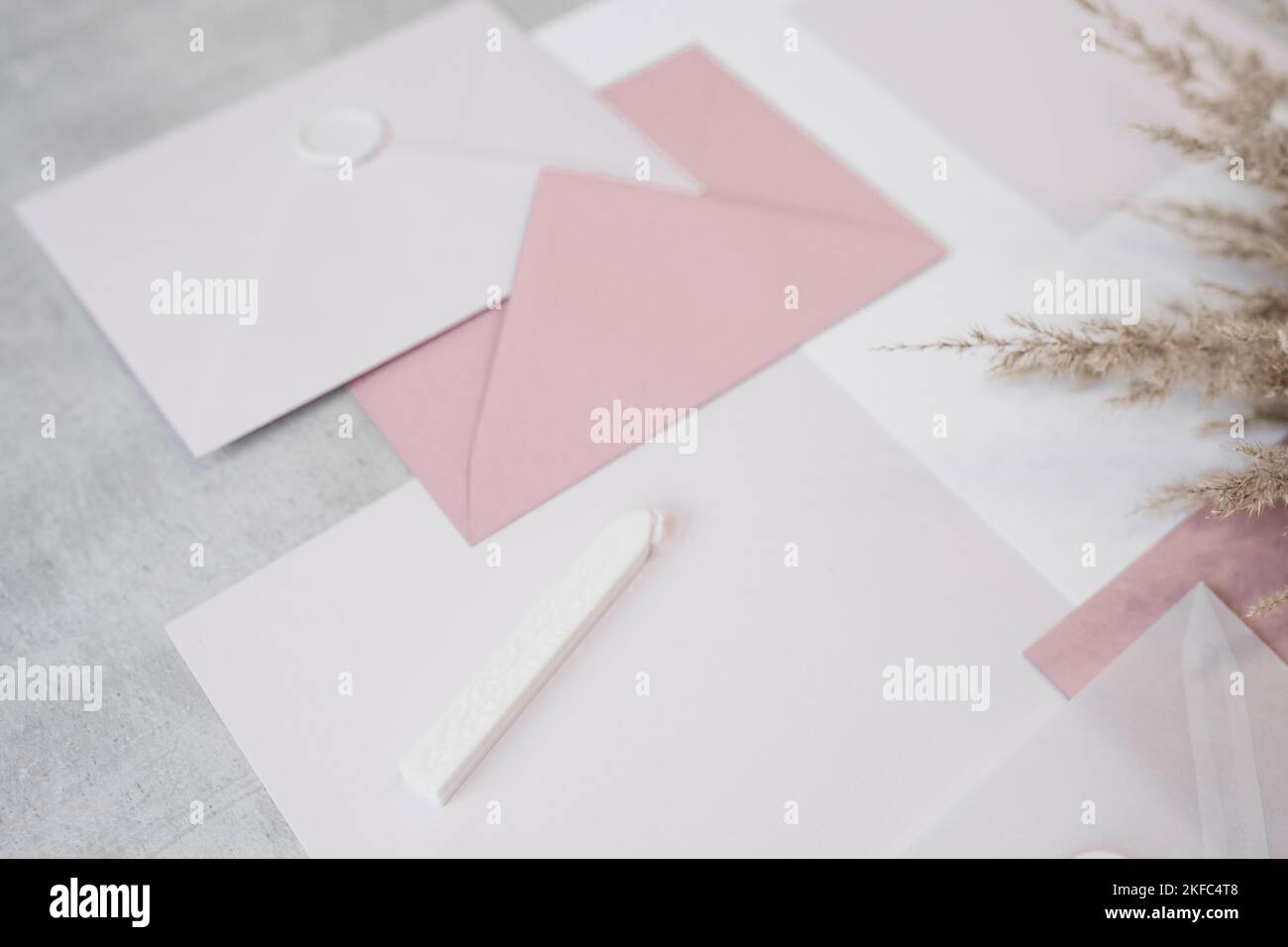 Vista dall'alto della composizione di fogli di carta di diverse dimensioni, buste bianche e rosa sigillate con cera, cera sigillante. Foto Stock