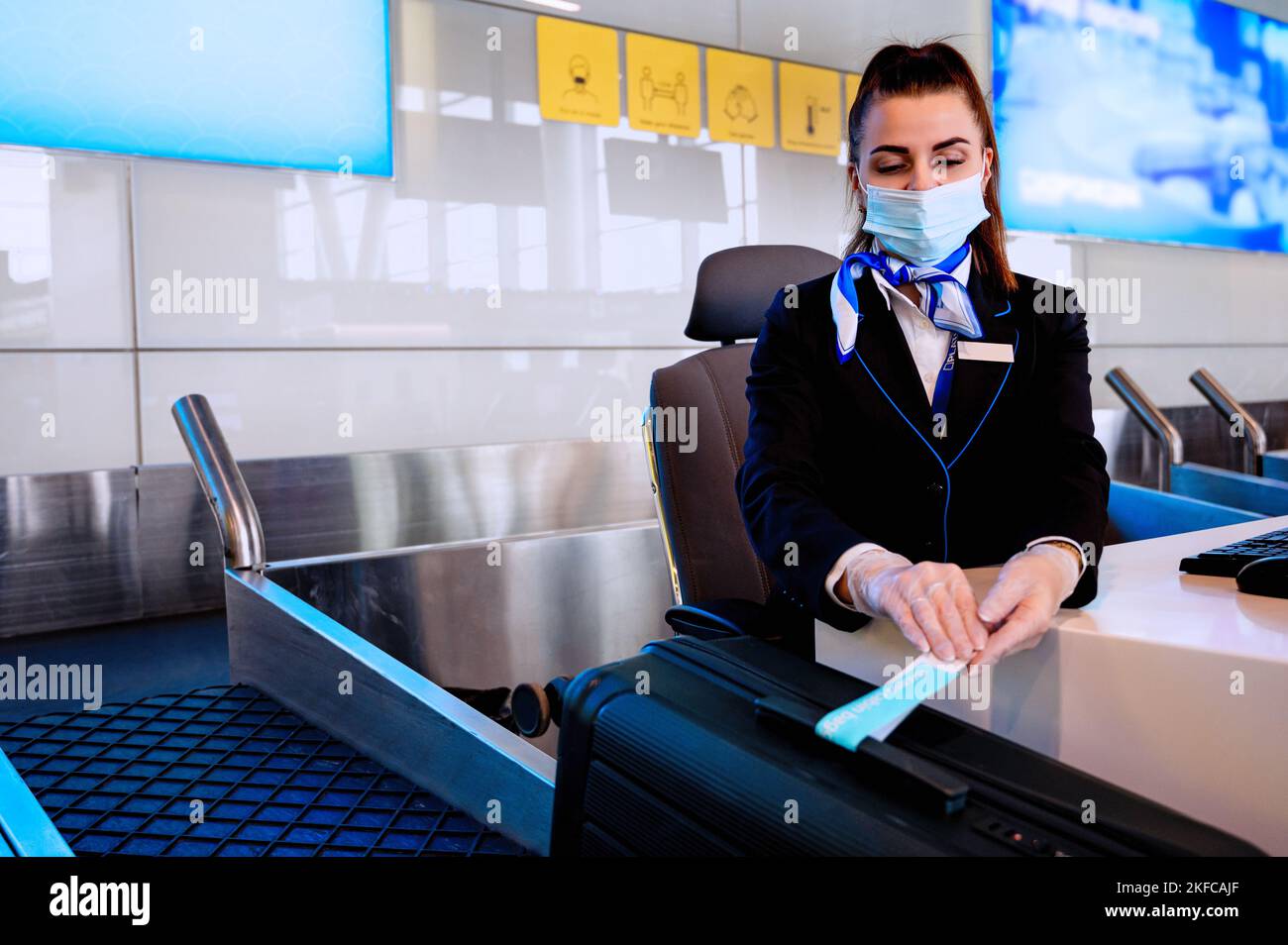 Il personale dell'aeroporto si siede al banco, pesando i bagagli e registrandosi Foto Stock