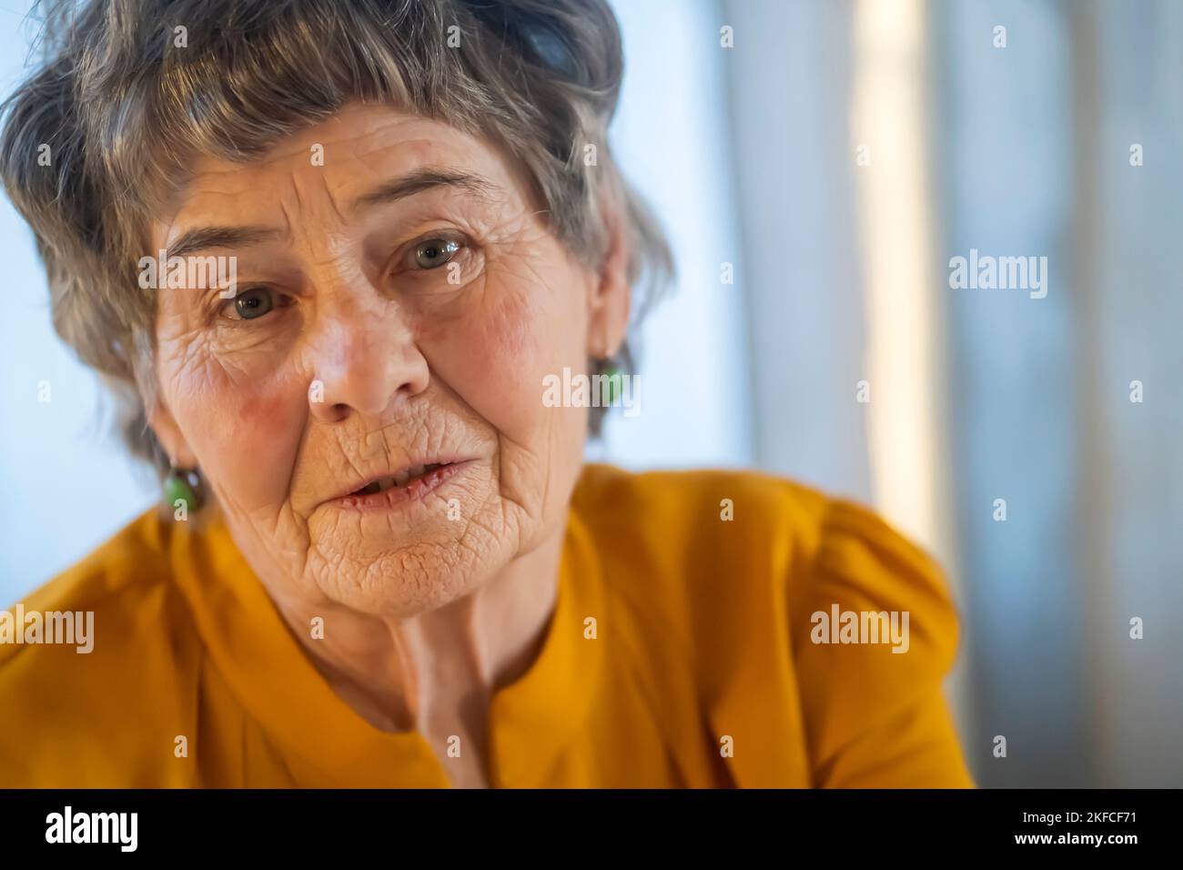 Vecchia donna in pensione con capelli grigi in blusa gialla. Foto Stock