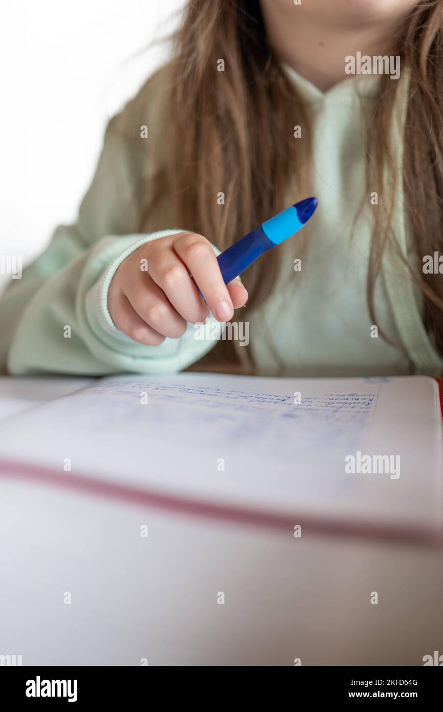 Homework.Study e Education.schoolgirl fa il suo lavoro. Il bambino scrive con una matita in un taccuino.la matita di primo piano in una mano del childs. Foto Stock