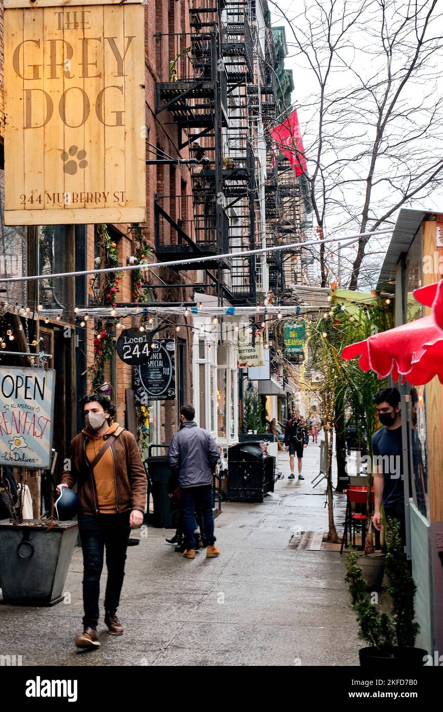 Le persone con maschere a piedi per strada in Little Italy quartiere a New York City Foto Stock