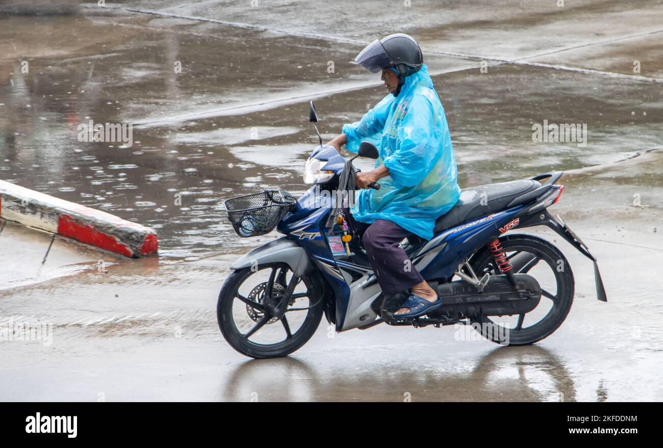 SAMUT PRAKAN, THAILANDIA, 26 2022 SETTEMBRE, il mototaxi driver in un giro di impermeabile blu sulla strada Foto Stock