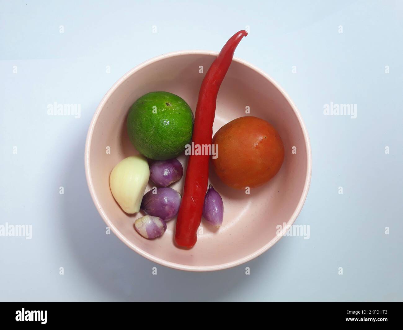 Primo piano isolato su erbe bianche, spezie aglio, cipolla, peperoncino, foglia di lime e pomodoro su recipiente rosa. Ingrediente condimento per cibo di cottura Foto Stock Primo piano isolato su erbe bianche, spezie aglio, cipolla, peperoncino, foglia di lime e pomodoro su recipiente rosa. Ingrediente condimento per cibo di cottura Foto Stock