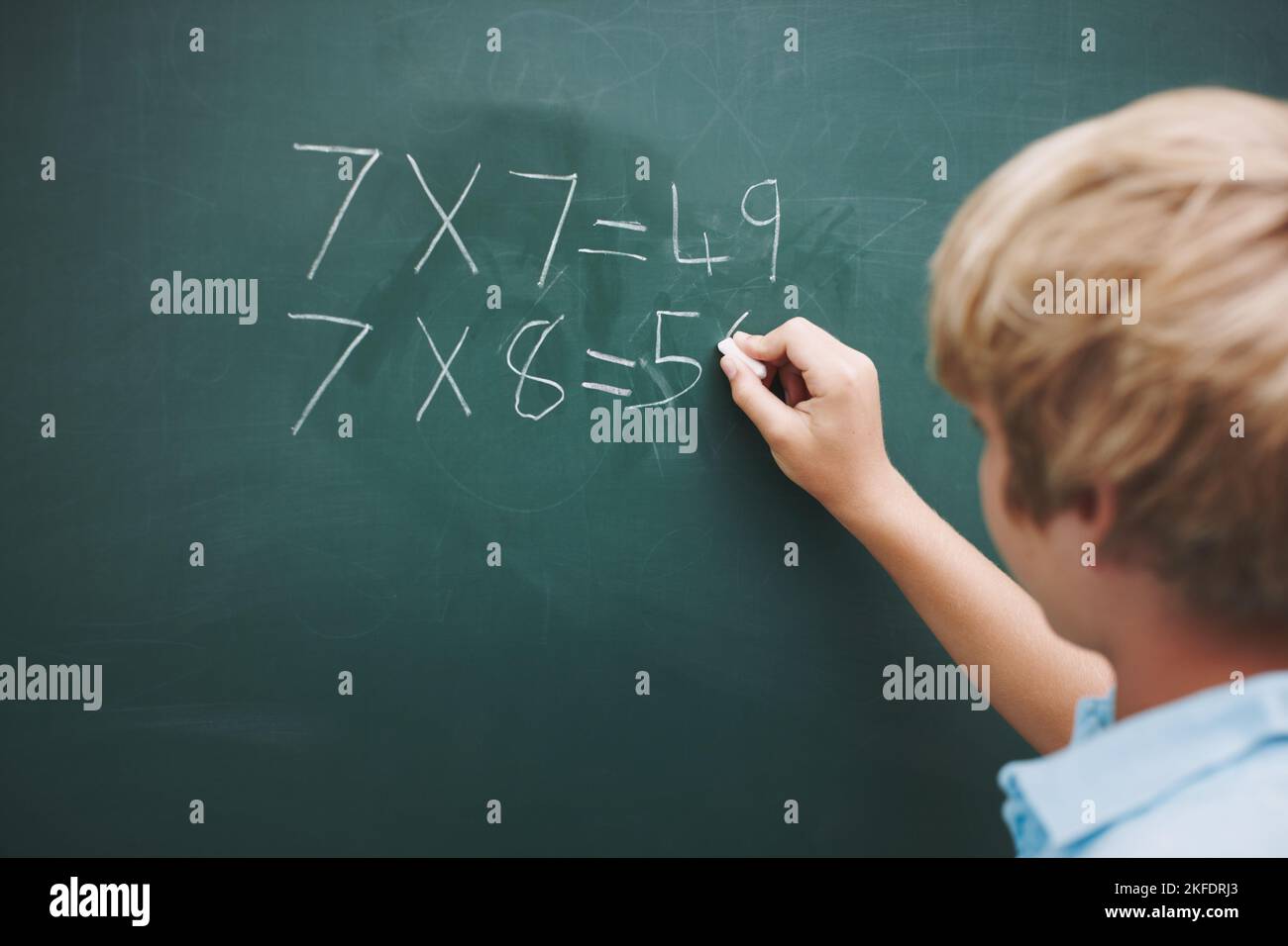 Ottenere buoni in matematica. Un ragazzo che fa le sue somme su una lavagna con un pezzo di gesso - copyspace. Foto Stock