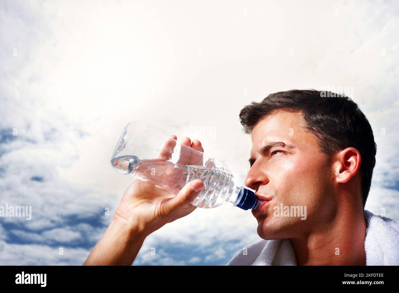 Giovane ragazzo intelligente che beve acqua - CopySpace. Primo piano di un giovane ragazzo intelligente che beve acqua dalla bottiglia contro il cielo. Foto Stock