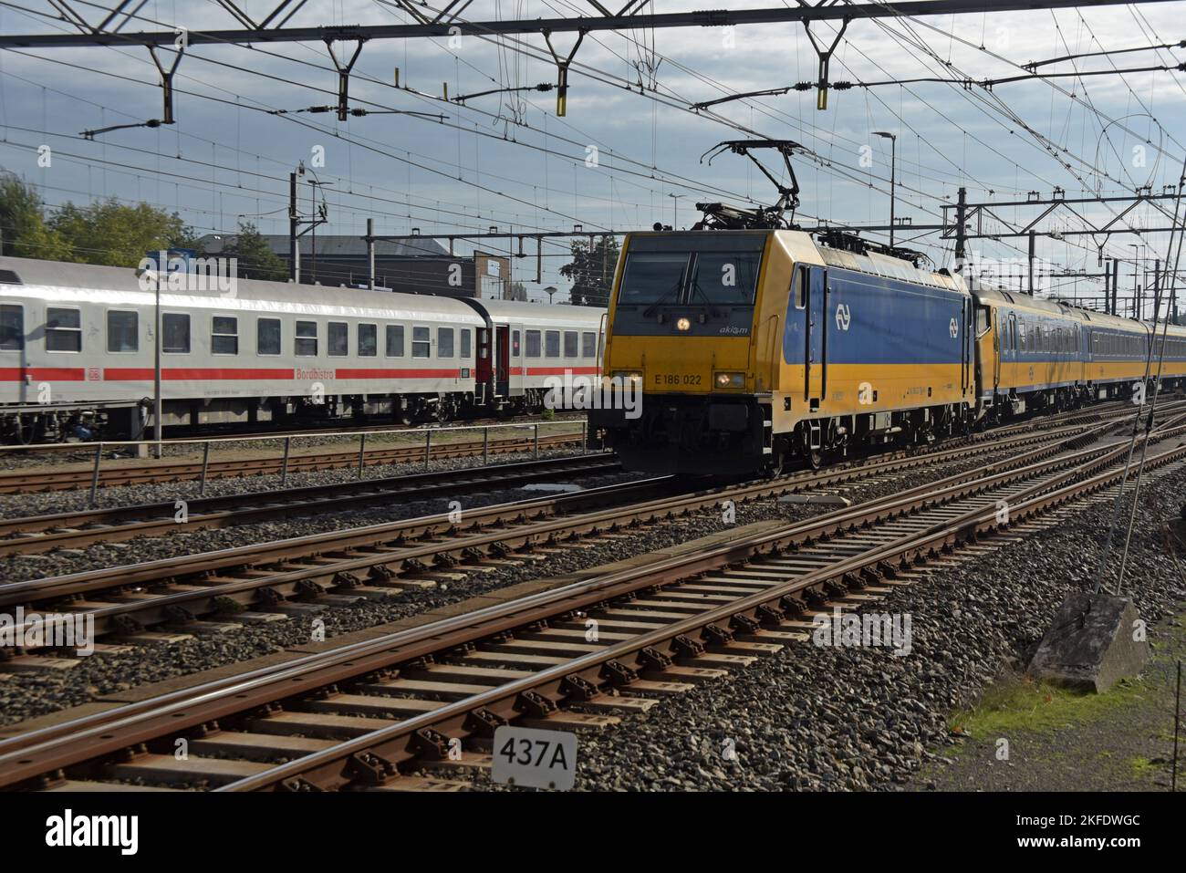 Treno della Deutsche Bahn in un quartiere di Amsterdam in preparazione per un viaggio di ritorno in Germania, con una locomotiva elettrica interurbana di classe 186 che passa. Foto Stock