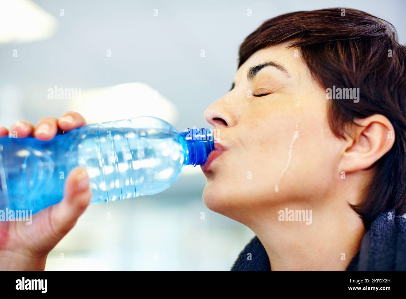 Idratazione e allenamento. Primo piano di bella donna che beve acqua dopo l'allenamento in palestra. Foto Stock