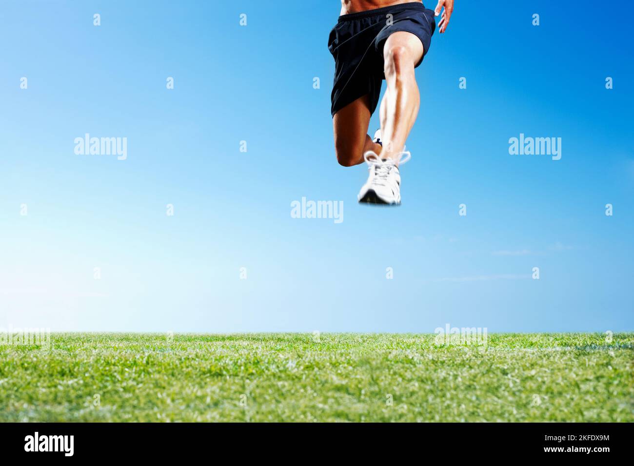 Giovane uomo che salta sull'erba contro il cielo. Immagine ritagliata di un giovane uomo che salta sull'erba verde contro il cielo - CopySpace. Foto Stock