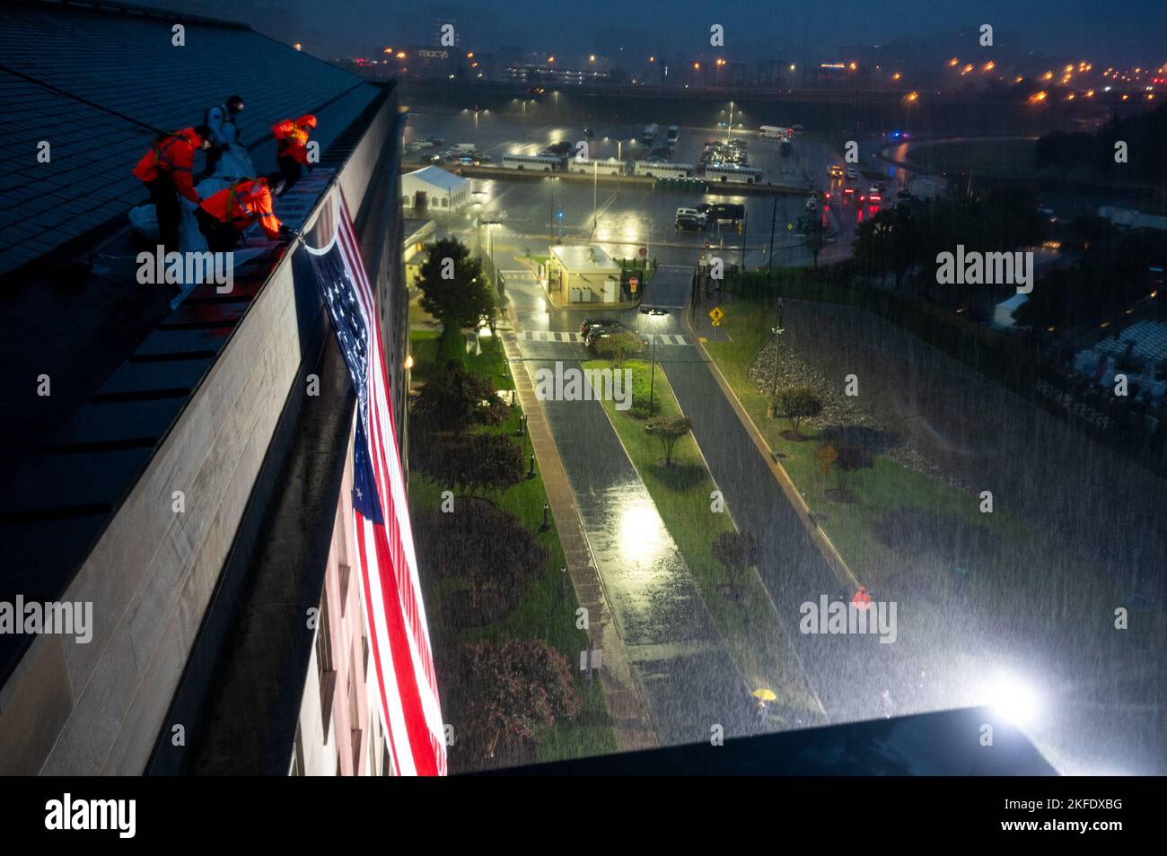 I funzionari del Pentagono hanno srotolato una bandiera americana sopra il lato del Pentagono nella pioggia durante una cerimonia di osservanza al memoriale nazionale del Pentagono 9/11 per onorare le 184 vite perse nell'attacco terroristico del 2001 al Pentagono, Washington, D.C., 11 settembre 2022. Foto Stock