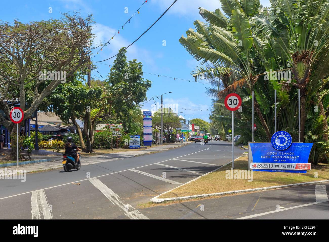 La città di Avarua, Rarotonga, Isole Cook. La strada principale, che porta all'area dello shopping. Un segno celebra il 50th° anniversario dell'indipendenza Foto Stock