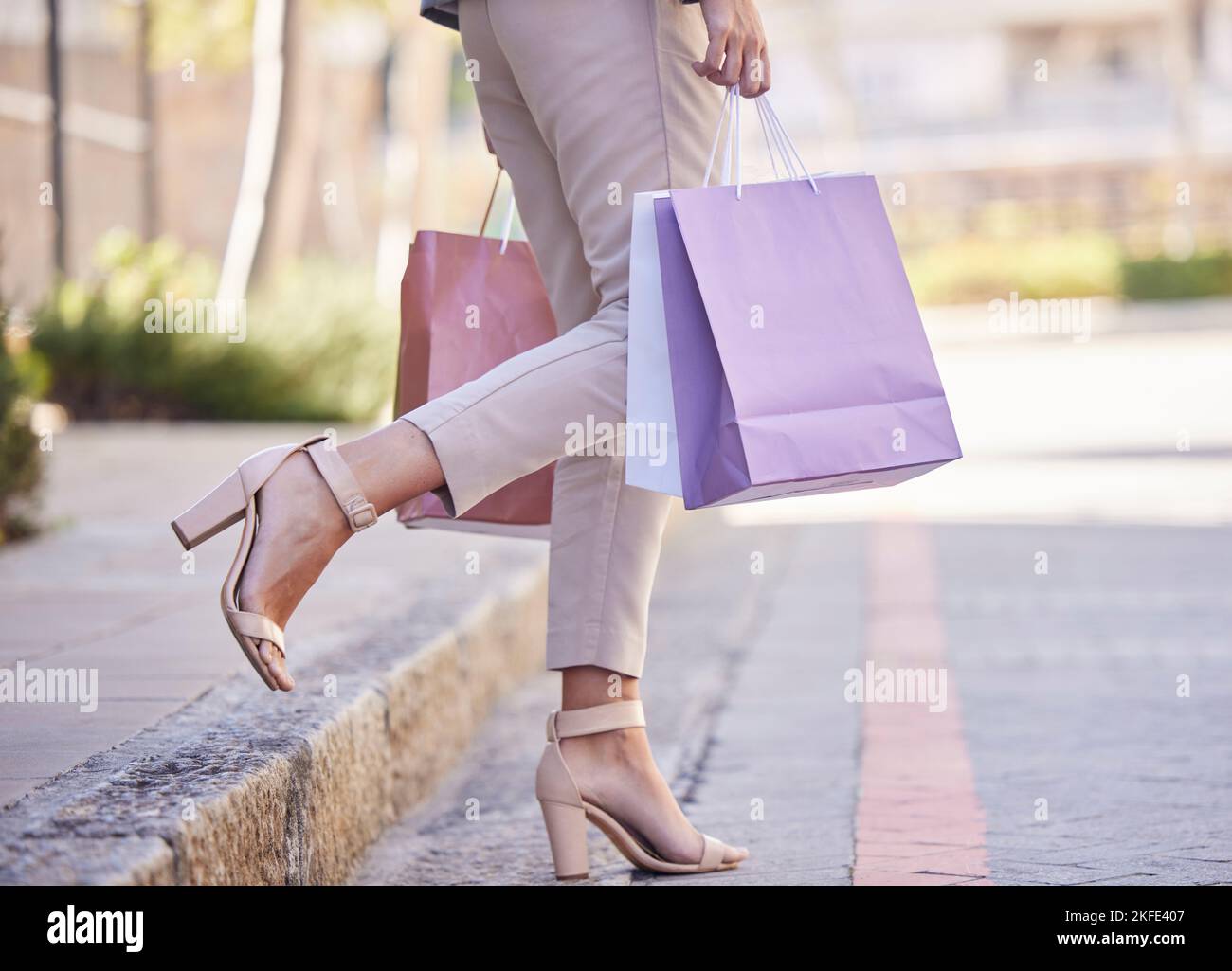Shopping bag, donna cliente e città strada per la vendita al dettaglio di moda, abbigliamento o lusso. Sconti, vendita e scelta estiva di scarpe, gambe e piedi per bambina Foto Stock