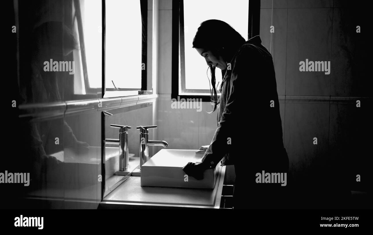 Donna sofferente di fronte allo specchio del bagno in disturbo mentale sensazione di ansia in monocromatico Foto Stock