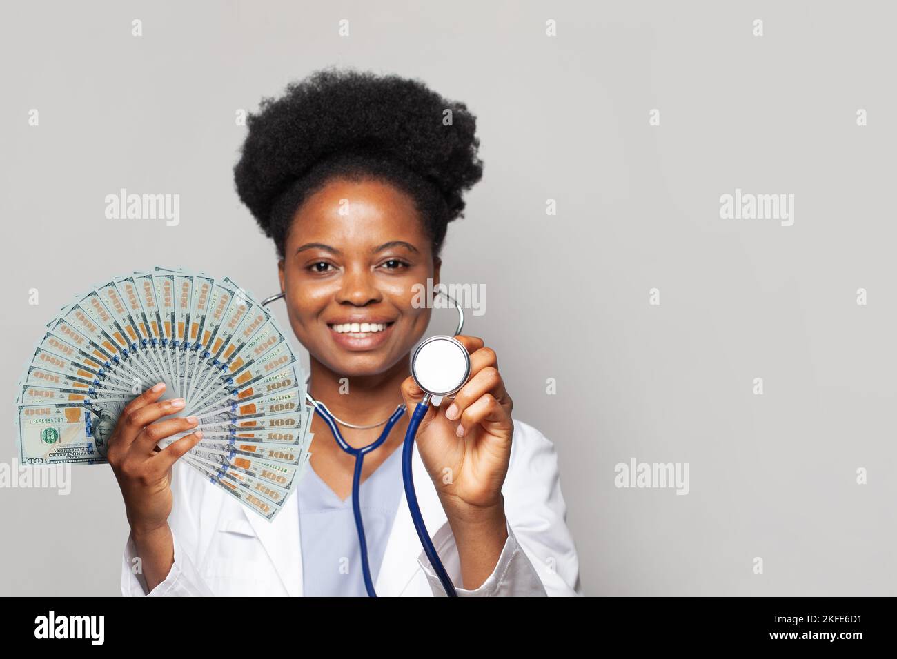Bella afro-americana donna medico tiene fan di soldi cento dollari fatture Foto Stock