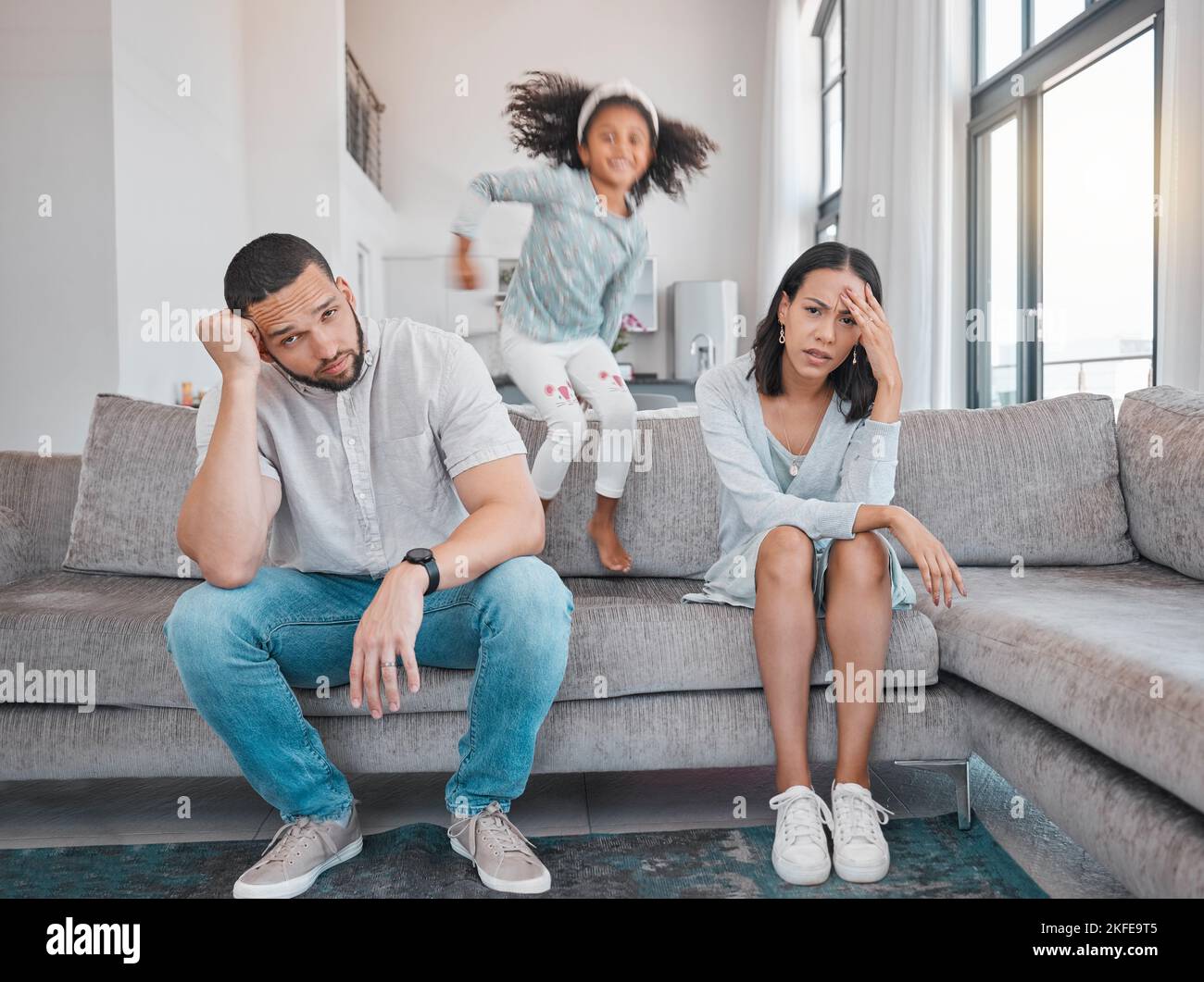 Stanco, la coppia e la famiglia con adhd ragazza salto veloce sul divano in casa soggiorno o casa. Uomo, donna e genitori con burnout, depressione o ansia Foto Stock