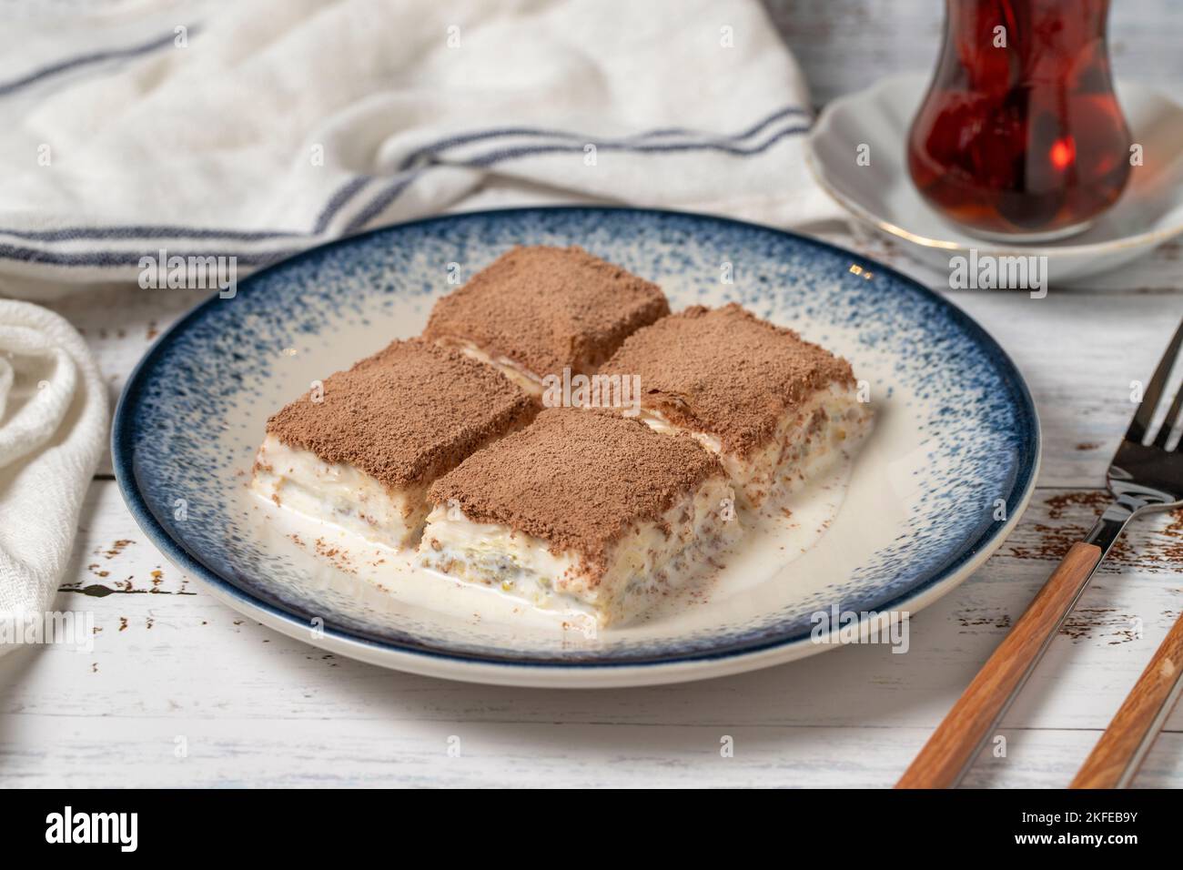 Baklava fredda su uno sfondo di legno bianco. Baklava con latte e pistacchio. Specialità della cucina mediterranea. Primo piano Foto Stock