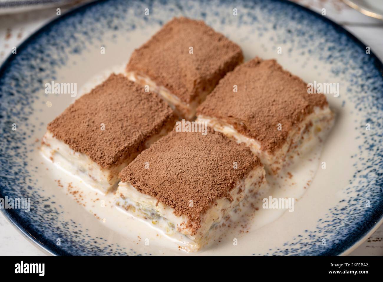 Baklava fredda su uno sfondo di legno bianco. Baklava con latte e pistacchio. Specialità della cucina mediterranea. Primo piano Foto Stock