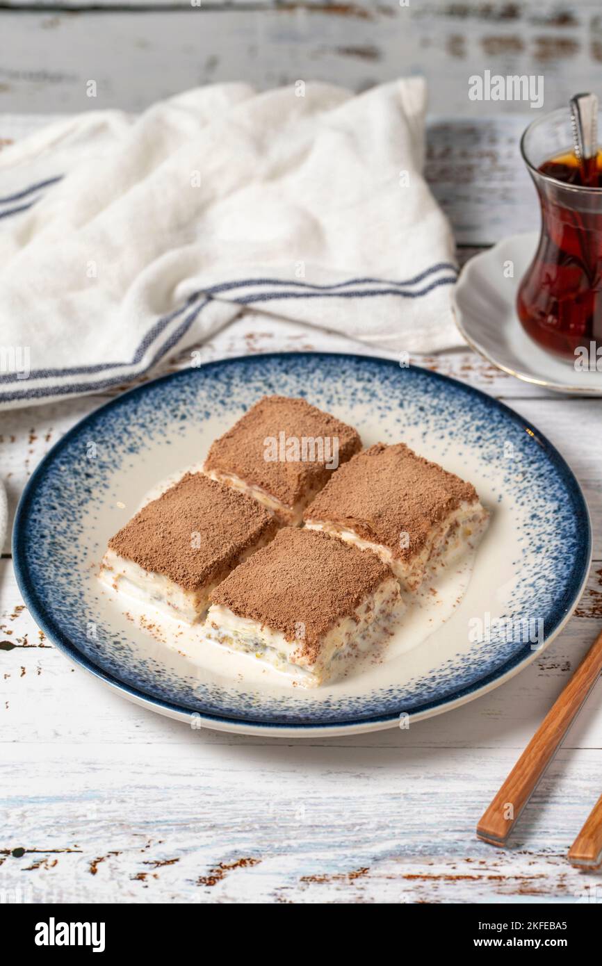 Baklava fredda su uno sfondo di legno bianco. Baklava con latte e pistacchio. Specialità della cucina mediterranea. Primo piano Foto Stock