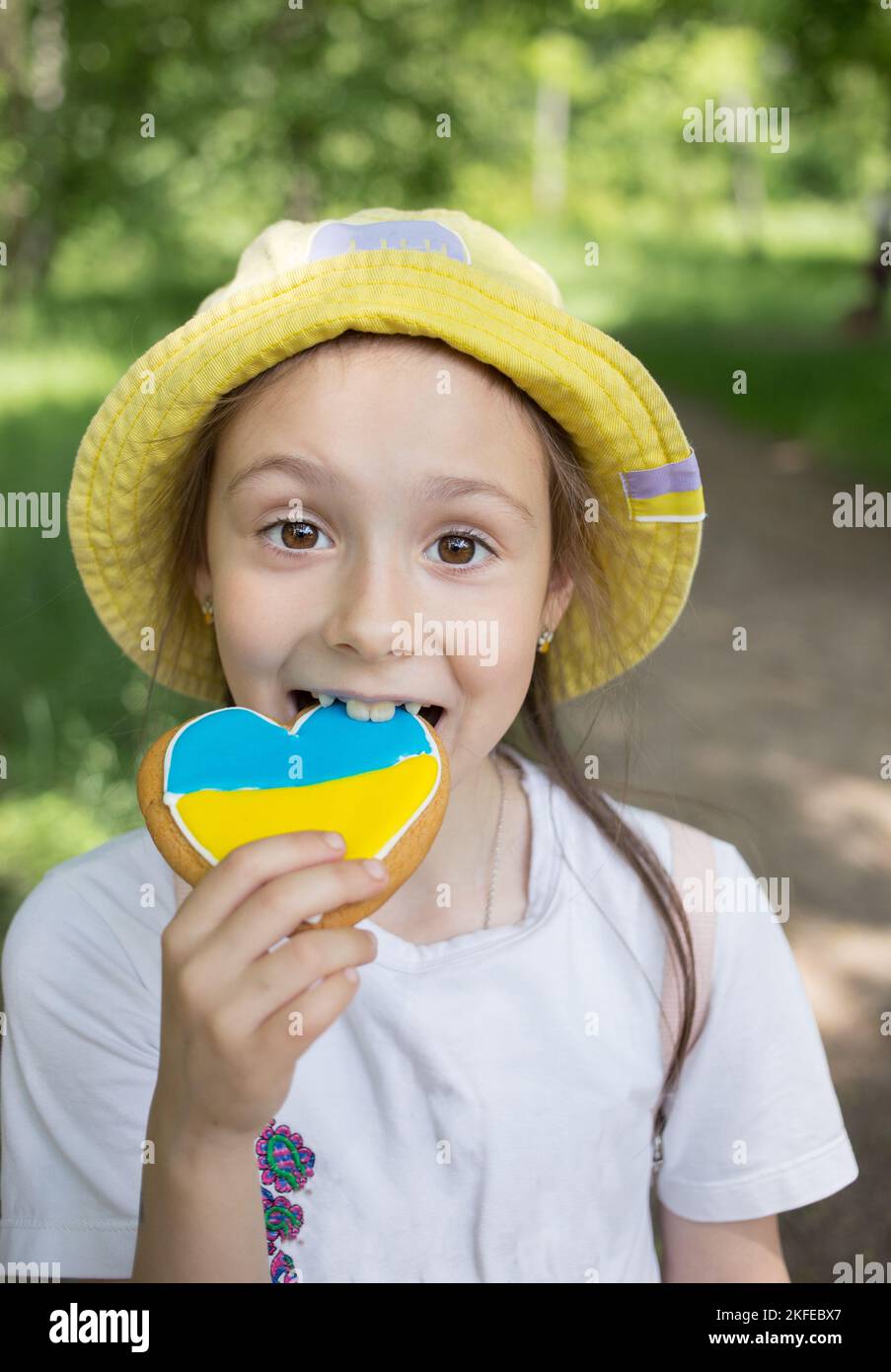 Ritratto facciale di una ragazza gioiosa carina di 7 anni con un pan di zenzero dipinto nei colori giallo-blu della bandiera Ucraina. Orgoglio di essere ucraino. L Foto Stock