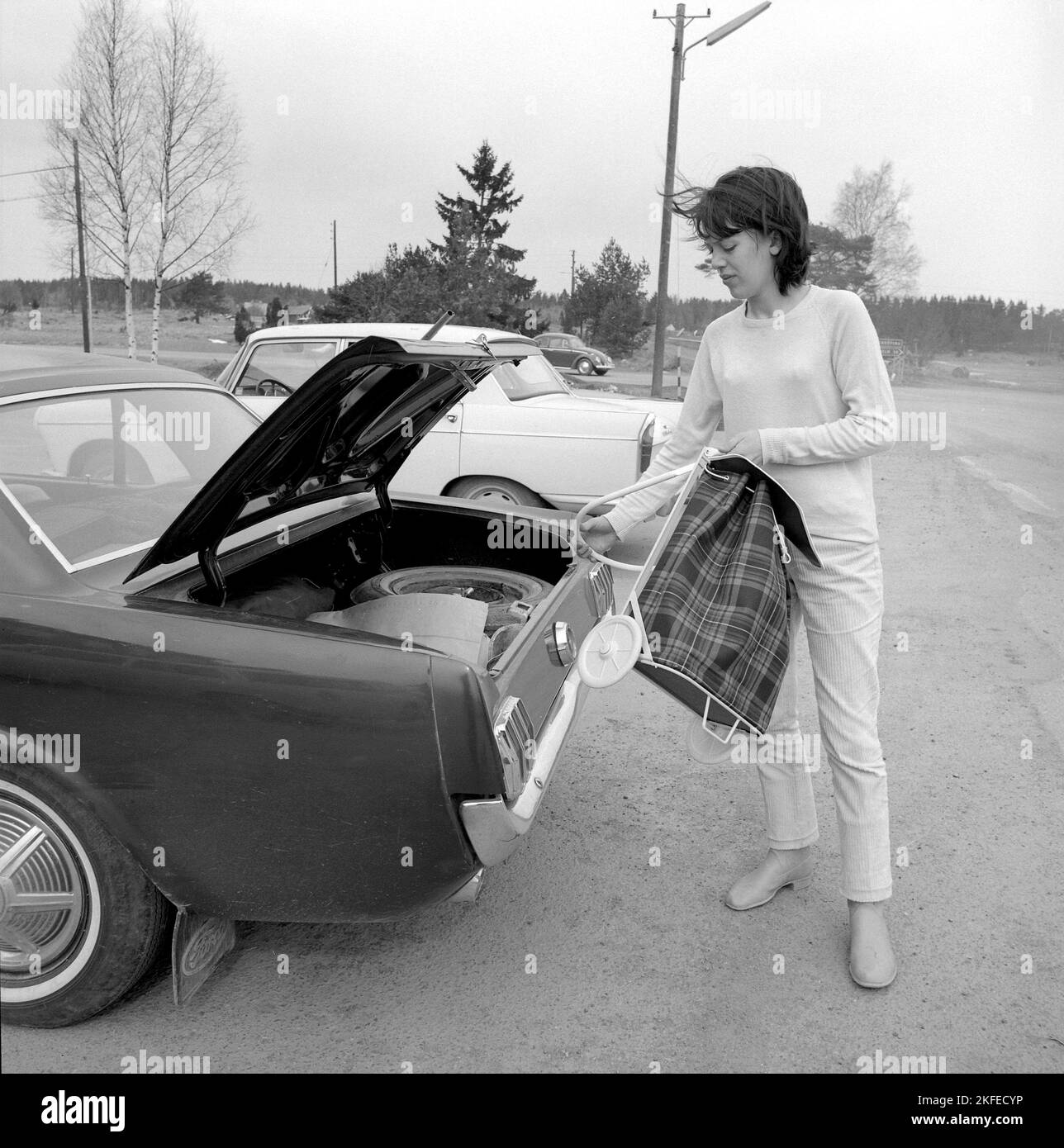 Shopping nel 1960s. Una signora ha parcheggiato la sua auto al supermercato e ha messo fuori il suo carrello nel parcheggio. Un articolo di novità che originariamente proveniva dagli Stati Uniti. Svezia aprile 14 1966 Conard Ref 5236 Foto Stock