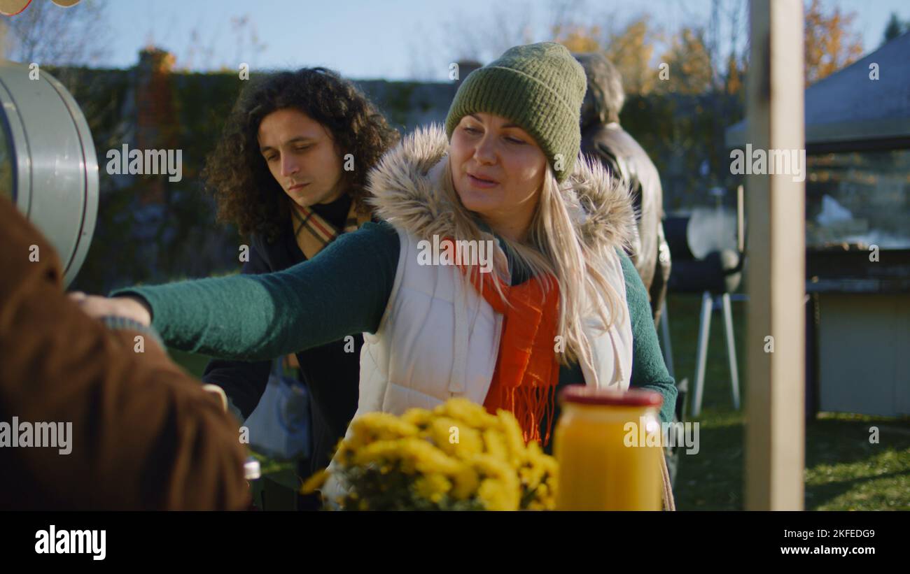 La donna adulta sceglie le mele alla bancarella con frutta e verdura. Persone che camminano e lo shopping sullo sfondo. Mercato agricolo locale o fiera all'aperto. Cibo vegetariano e biologico. Agricoltura. Foto Stock