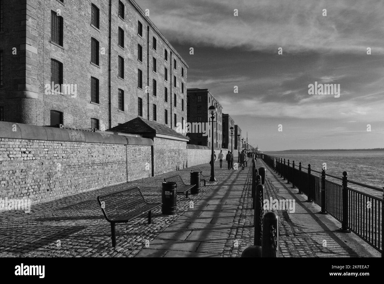 Sul lungomare di Livepoool, Merseyside, Regno Unito; a sinistra i magazzini ringiovaniti di Albert Dock, a sinistra il fiume Mersey Foto Stock