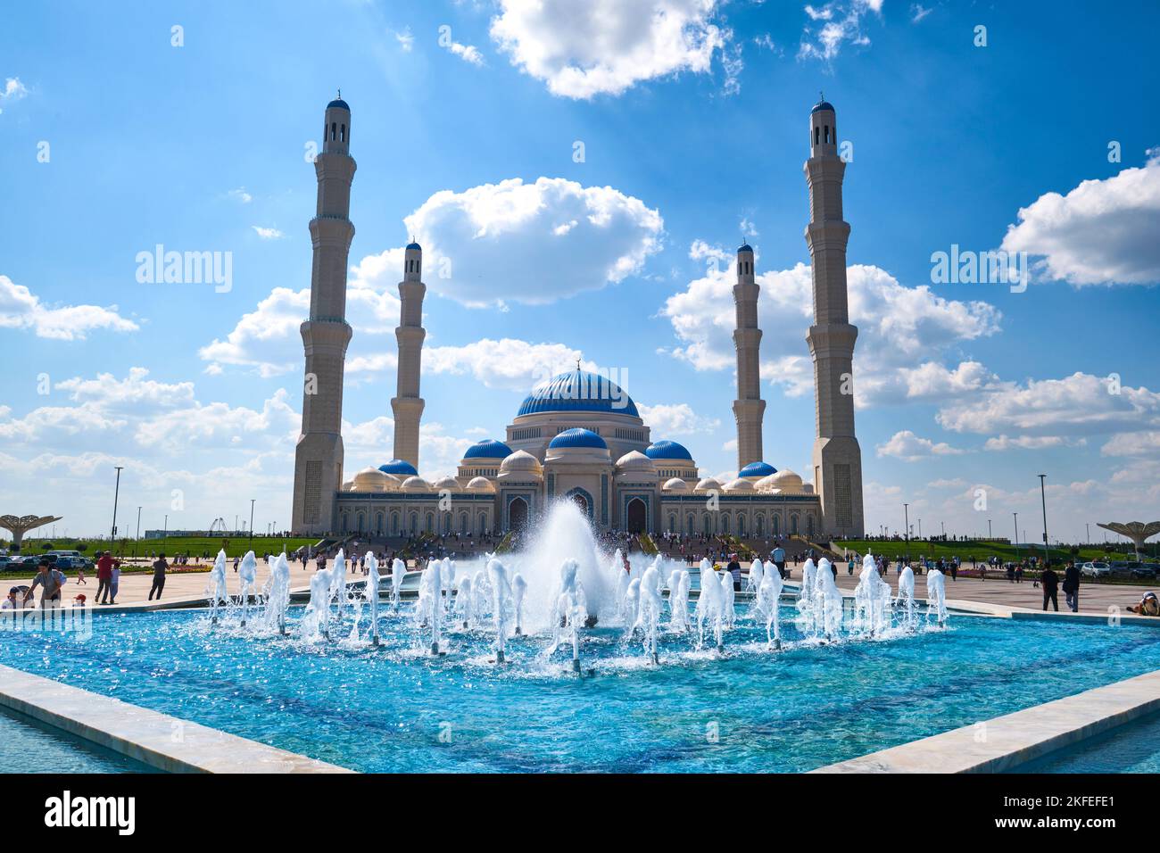 Una vista dell'entrata frontale dell'enorme moschea, con una serie di fontane d'acqua blu nella piazza. Alla nuova apertura nel 2022, la Grande Moschea di asta Foto Stock