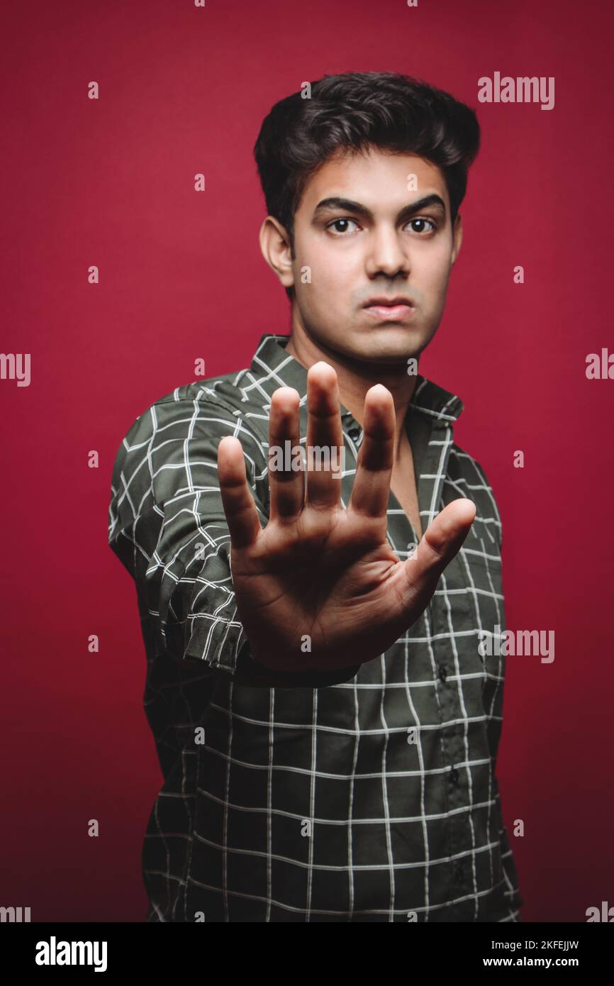 Indian Man Using Stop Gesture (uomo indiano che utilizza il gesto di arresto) – avvertimento contro le minacce di intelligenza artificiale e i crimini informatici. Un uomo indiano è raffigurato con il palmo spalancato in un forte gesto di arresto Foto Stock