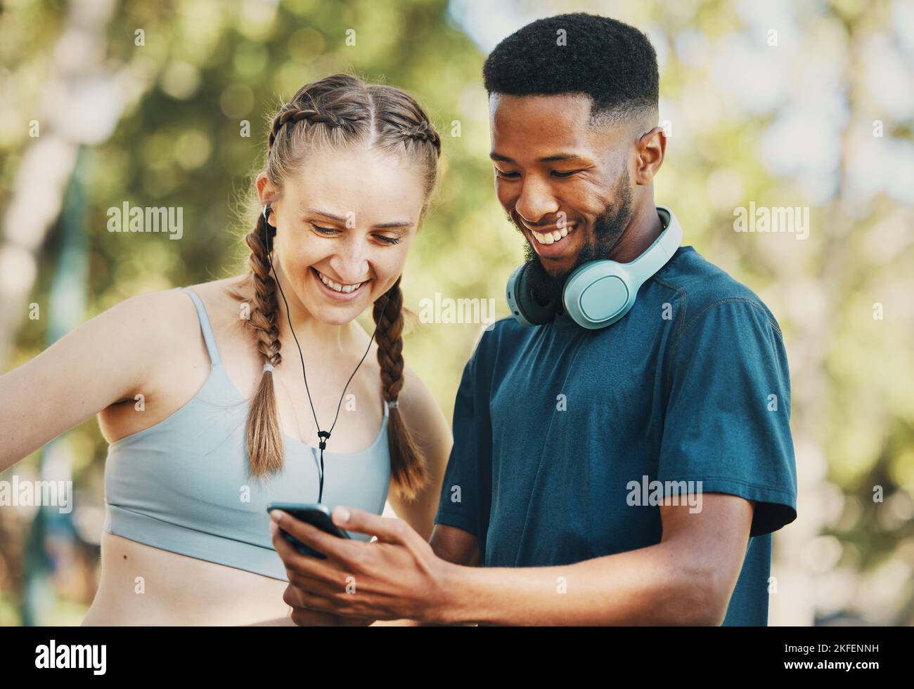 Fitness, social media e coppia con il telefono in un parco per la formazione, app mobile e video divertenti. Comunicazione, commedia e nero uomo e donna lettura Foto Stock