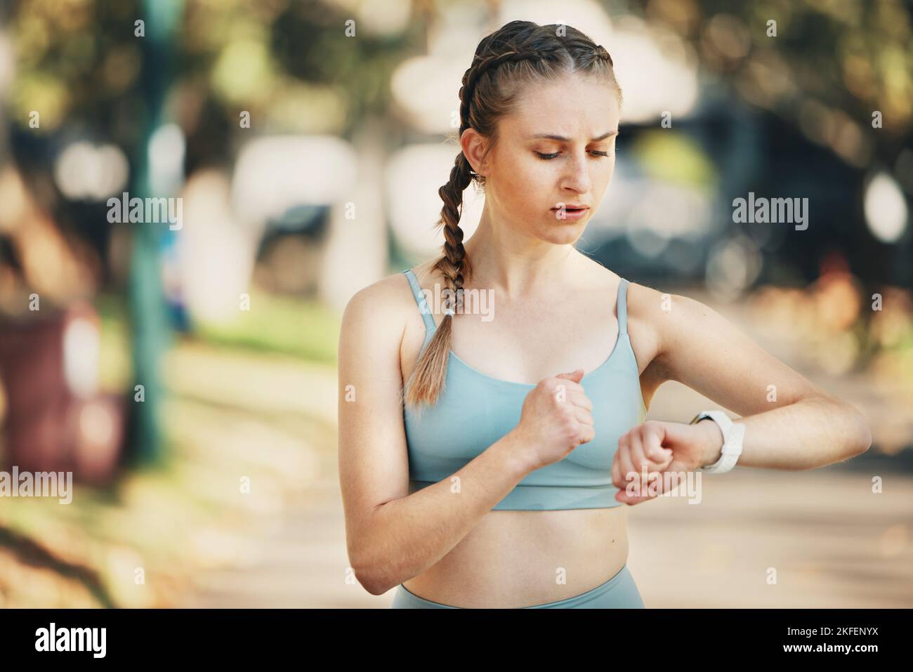 Fitness, guardare il tempo e l'allenamento di una donna allenamento e controllare il polso cardiaco in un parco all'aperto. Runner wellness, Steps e app per la tecnologia Smart Watch Foto Stock