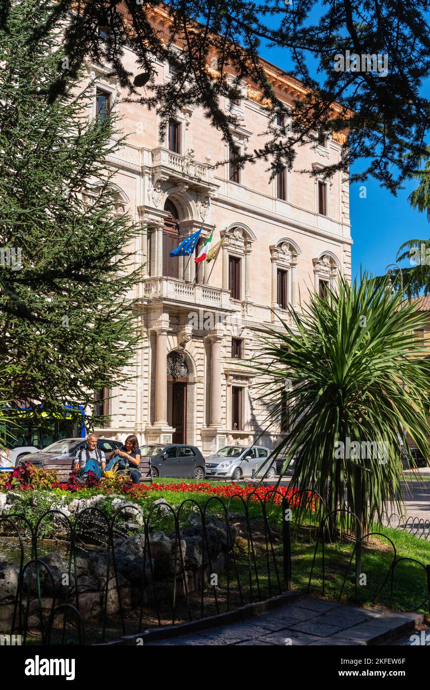 Veduta di Palazzo Cesaroni, sede del Consiglio Regionale dell'Umbria, tra gli alberi del parco di Piazza Italia. Perugia, Umbria, Italia, Europa Foto Stock