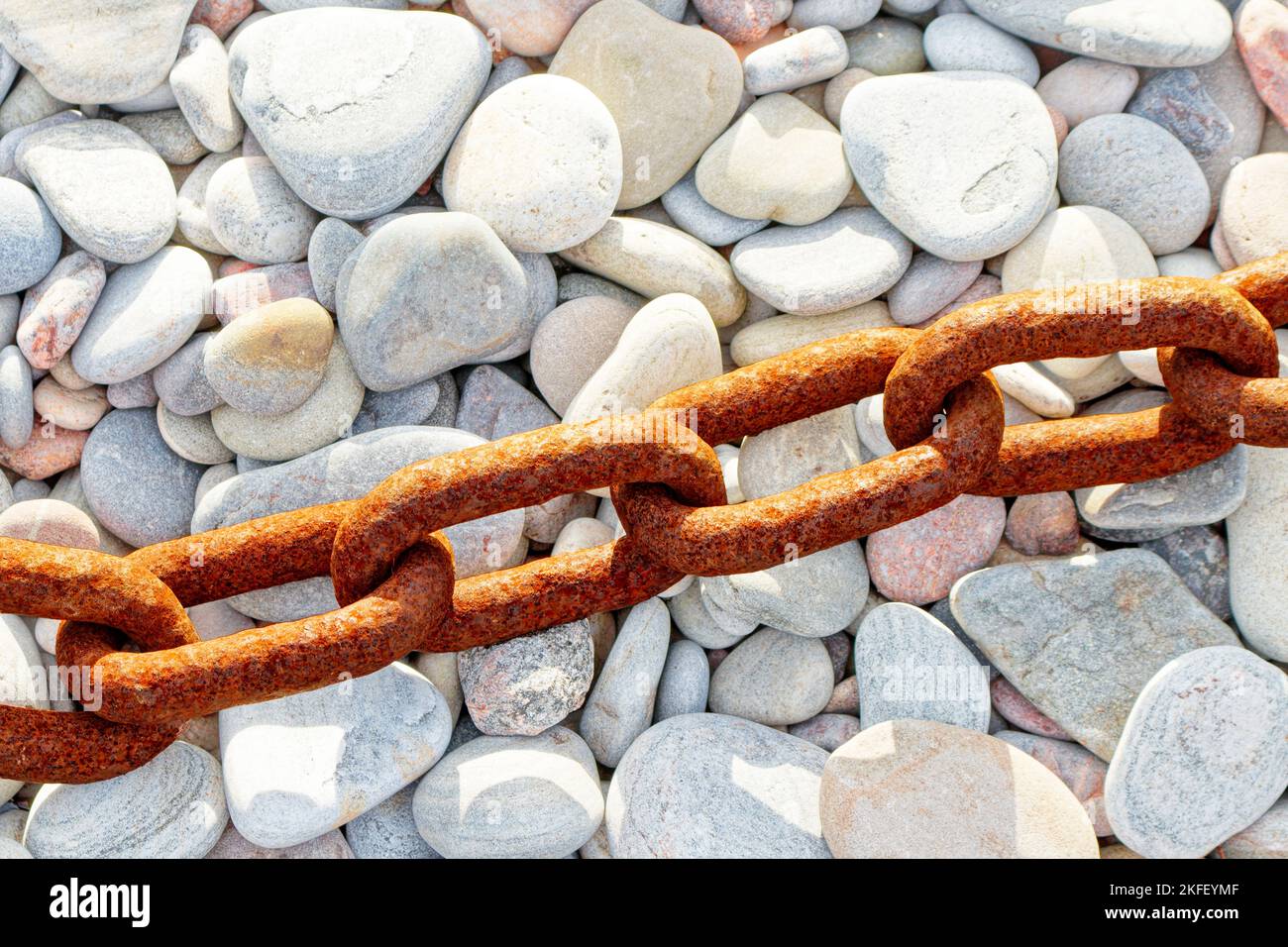 Vecchia catena di metallo arrugginita ruvida e maglie che poggiano su una spiaggia di ciottoli Foto Stock