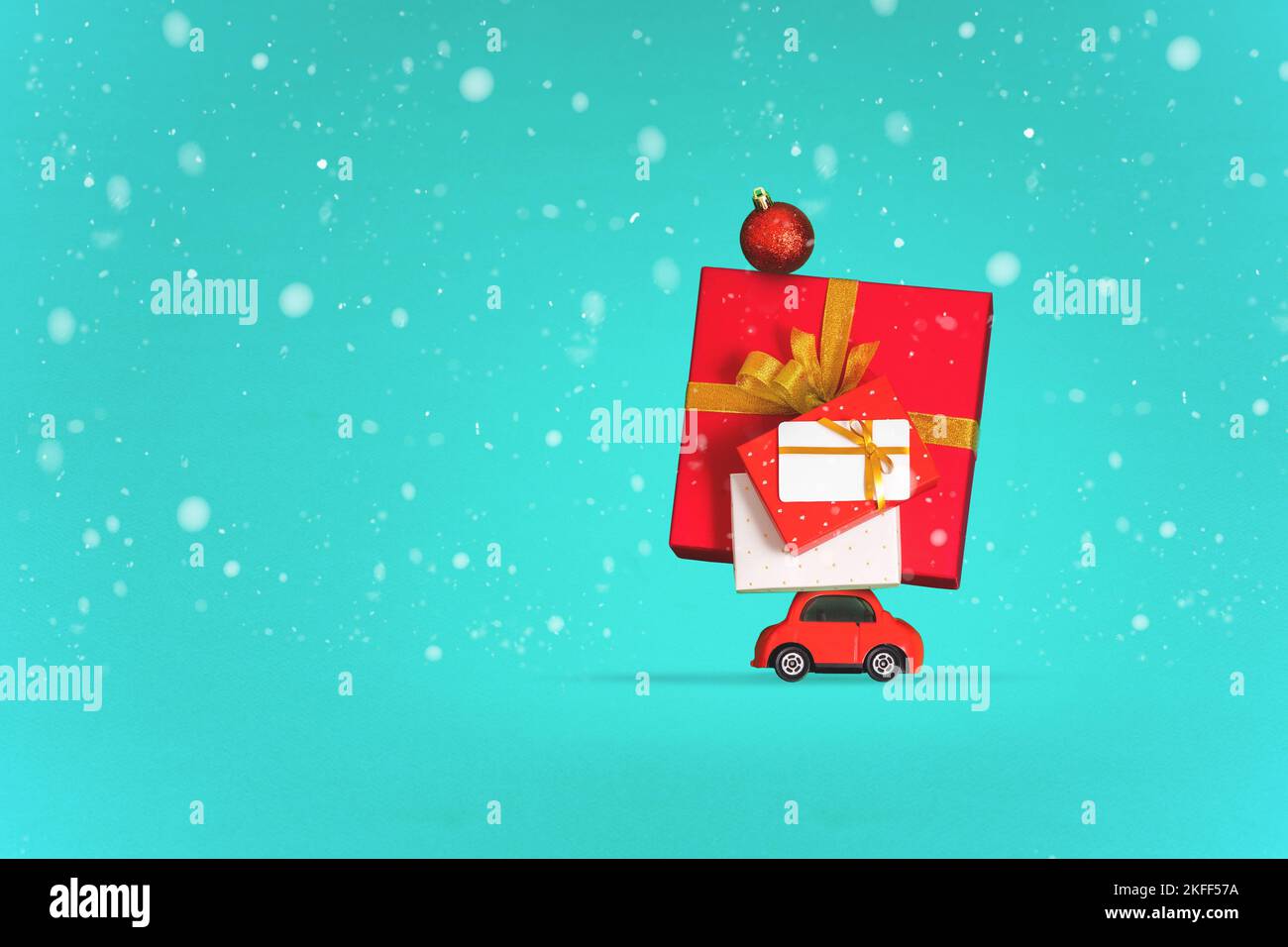 Minimal Christmas Card Concept, red Small car trasporta molti regali di Natale sotto nevicate, sfondo blu. Nuovo sfondo creativo per i vacanzieri Foto Stock