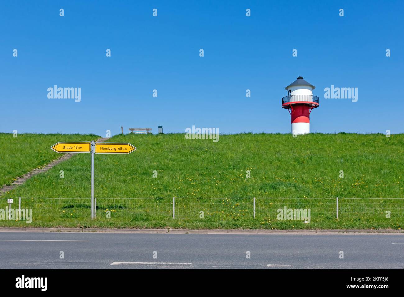 A red and white lighthouse towers over a dike in the Alte Land near Lühe, Germany Foto Stock